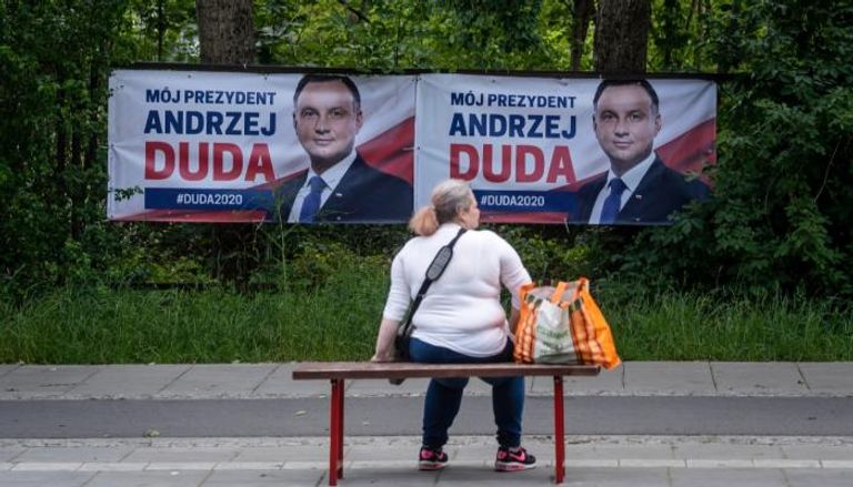 امرأة تجلس أمام ملصق انتخابي في بولندا 