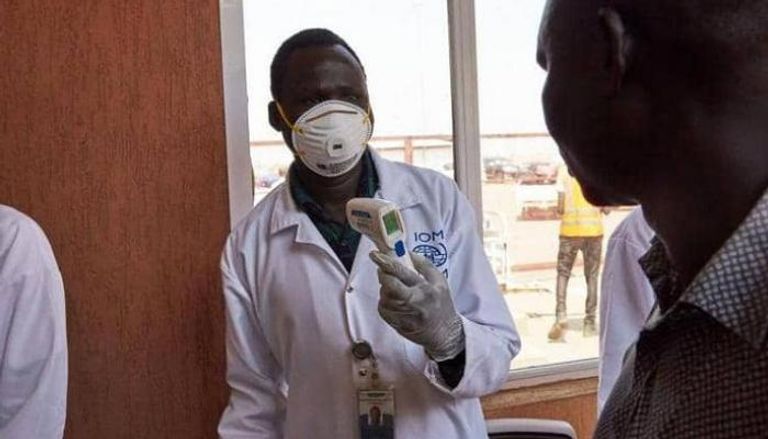طبيب سوداني يجري كشف الحرارة على أحد الأشخاص