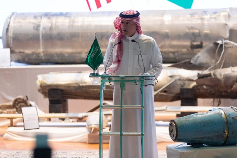 الجبير وبراين هوك في المؤتمر وخلفهما بقايا الأسلحة الحوثية