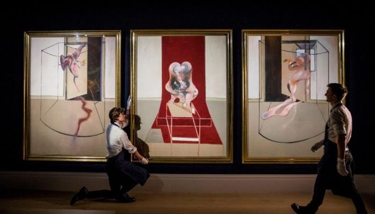 عاملان في دار المزادات يعدان اللوحة الثلاثية للرسام فرانسيس بيكون