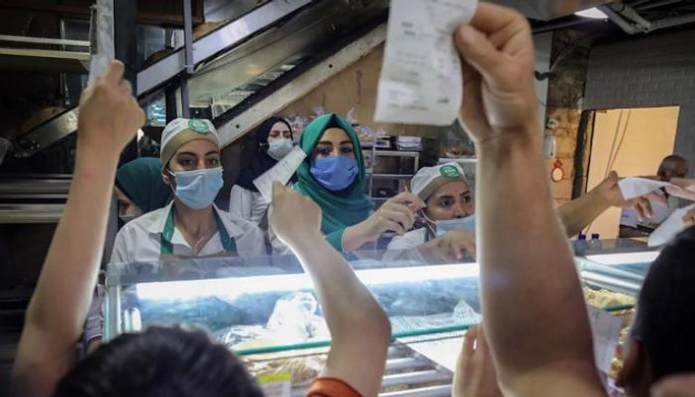 عمال يرتدون كمامات أثناء خدمة الزبائن في لبنان - تليجراف
