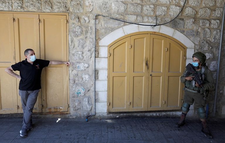 فلسطيني يرتدي الكمامة ينظر إلى جندي إسرائيلي يرتدي الكمامة أيضا في مدينة الخليل بالضفة رجل دين في الهند يرتدي كمامة وإلى جواره حارسه الشخصي