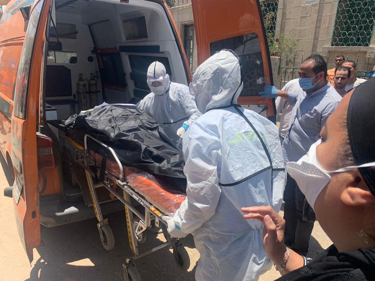 مسعفون يرتدون بدل واقية، ينقلون جثمان الفنانة المصرية الراحلة رجاء الجداوي، إلى مقابر البساتين وسط العاصمة المصرية القاهرة