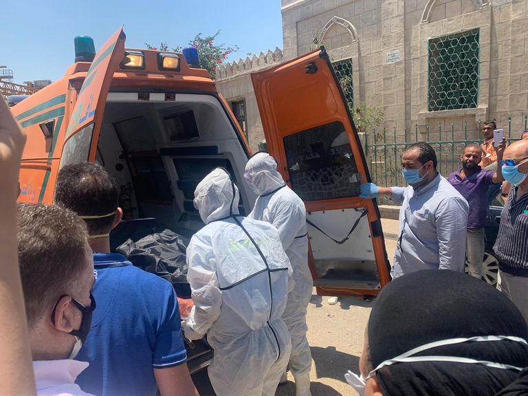 مسعفون يرتدون بدل واقية، ينقلون جثمان الفنانة المصرية الراحلة رجاء الجداوي، إلى مقابر البساتين وسط العاصمة المصرية القاهرة