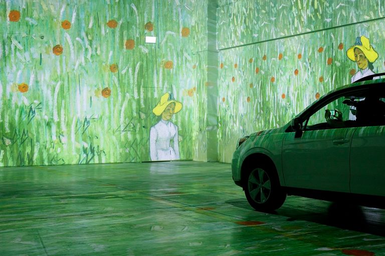 زوار معرض انغماسي لأعمال فان جوخ يطلعون من سياراتهم على المعروضات