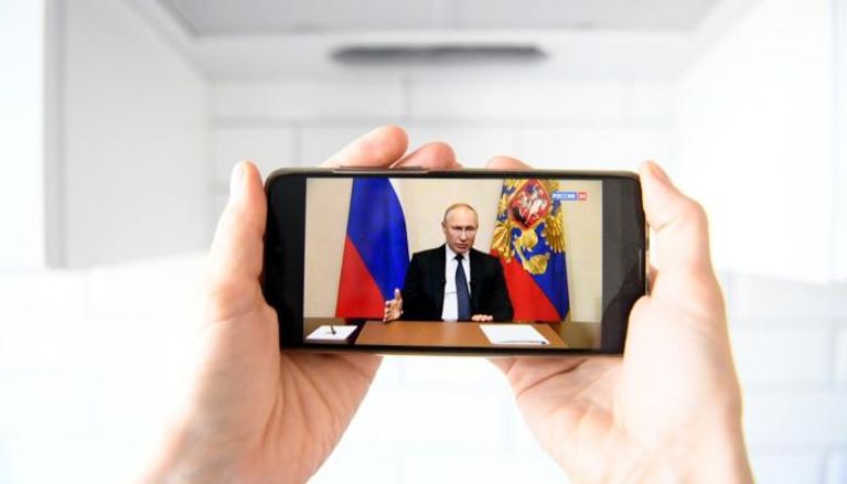 شخص يشاهد خطابا للرئيس بوتين عبر هاتفه 