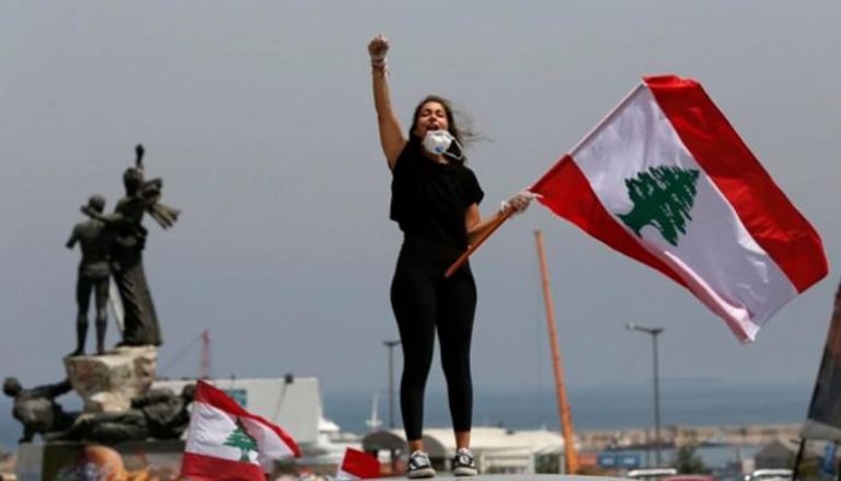 لبنانية تحمل علم بلادها خلال التظاهرات - أرشيفية