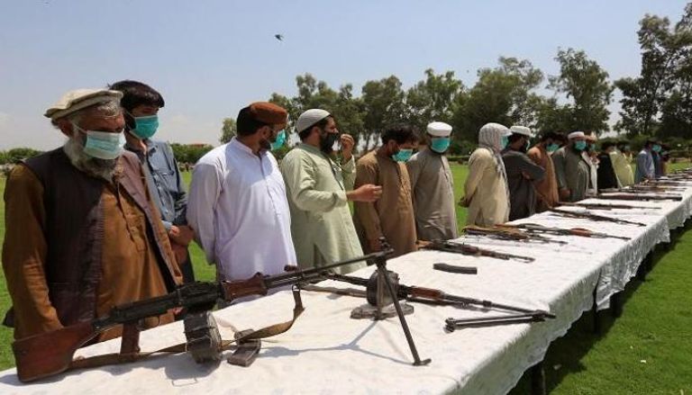 عناصر حركة طالبان وأمامهم أسلحة وذخيرة