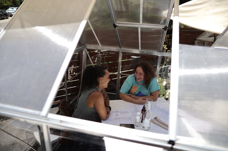 فتاتان تجلسان داخل إحدى الصوبات الزجاجية