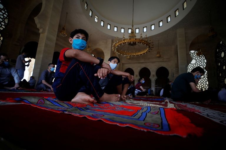 أم وابنتها ترتديان قناعا بينما تعبران طريقا في مدينة كلكتا الهندية