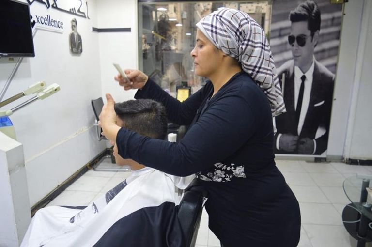 المصرية عبير مصطفى، أول مصففة شعر للرجال، تقوم بحلاقة شعر شاب عبير مصطفى تصفف شعر أحد زبائنها في صالونها الخاص