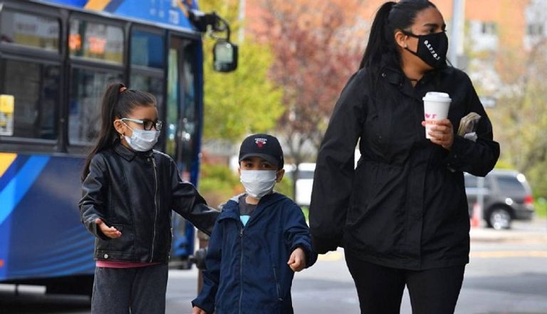 أم وطفليها يتجولون في أحد الشوارع ويرتدون الكمامة للوقاية من فيروس كورونا المستجد تعقيم اليدين للأطفال ضروري لتجنب عدوى كورونا