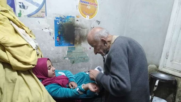 الطبيب المصري الراحل الدكتور محمد مشالي الذي عرف بـ"طبيب الغلابة" يقوم بالكشف على مريضة في عيادته الدكتور محمد مشالي