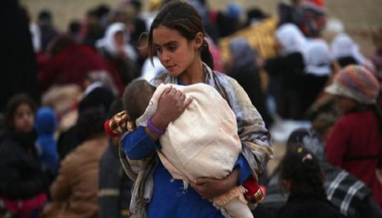 طفلة أيزيدية تحمل شقيقها الرضيع - أرشيفية