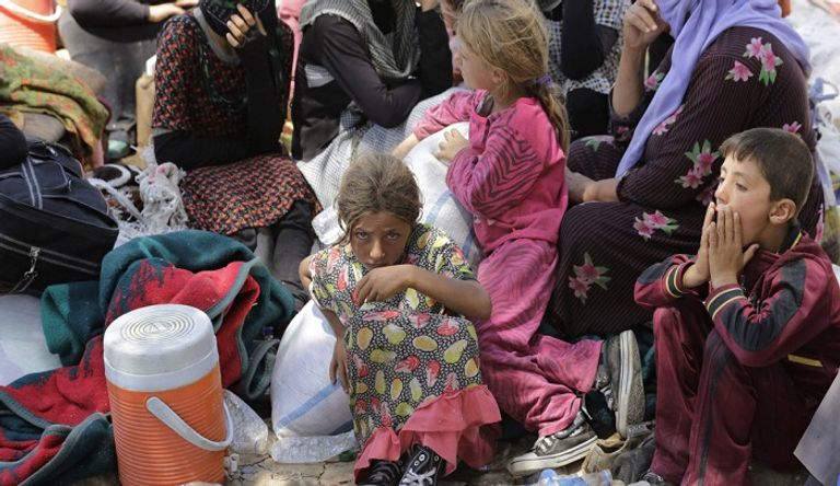 الخوف يعتري وجه طفلة أيزيدية بمخيم للاجئين- أرشيفية طفلة أيزيدية تحمل شقيقها الرضيع - أرشيفية