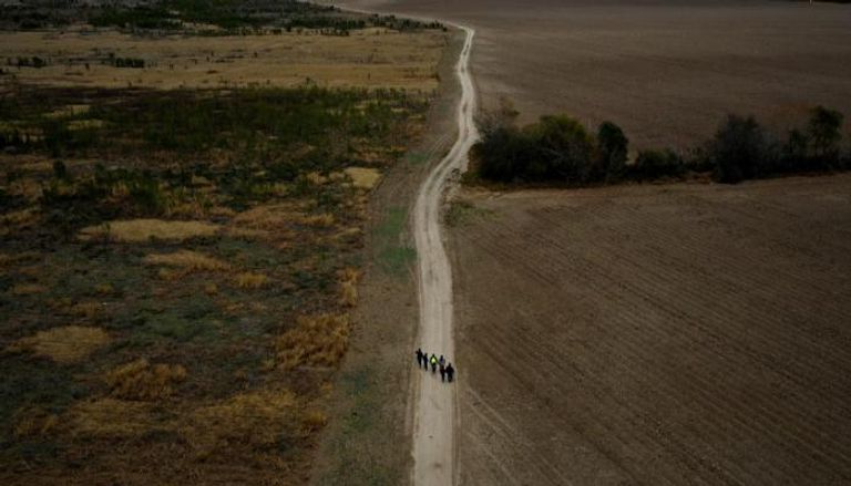 مهاجرون على طريق يصل للجدار بين أمريكا والمكسيك