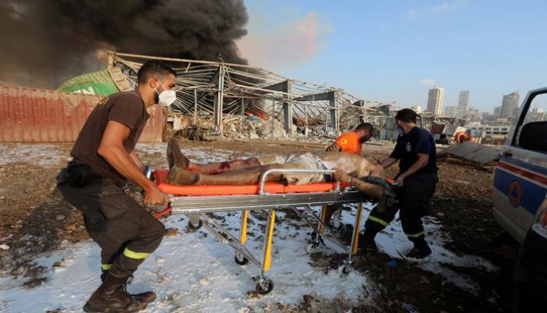 عاملون في الدفاع المدني ينقلون أحد ضحايا الانفجار الضخم الذي ضرب مرفأ بيروت