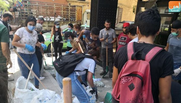 شباب يزيلون الزجاج المتناثر في شوارع بيروت