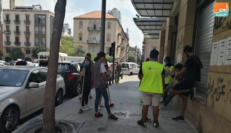 شباب يزيلون الزجاج المتناثر في شوارع بيروت