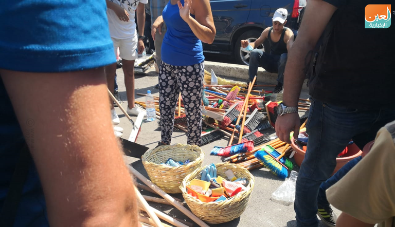 شباب يزيلون الزجاج المتناثر في شوارع بيروت