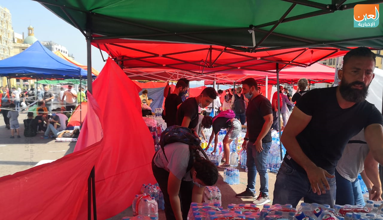 شباب يزيلون الزجاج المتناثر في شوارع بيروت