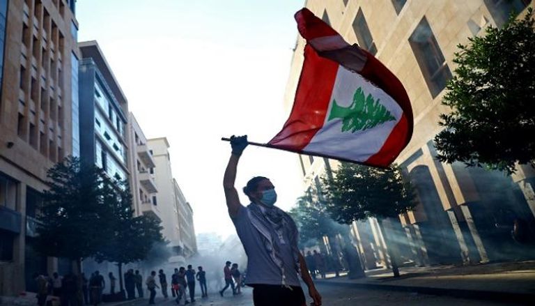 لبناني يلوح بعلم بلاده خلال الاحتجاجات للمطالبة بإسقاط الطبقة الحاكمة
