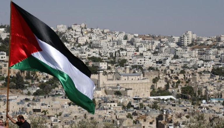 فلسطيني يرفع علم بلاده في الضفة الغربية 