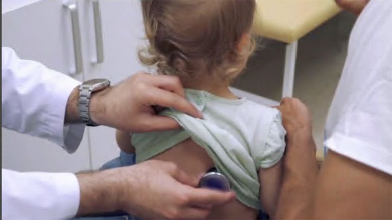 طبيب يكشف على طفلة طفلة تضع كمامة للوقاية من كورونا