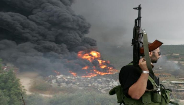 أحد مسلحي حزب الله ينظر إلى حريق بإحدى ضواحي بيروت 