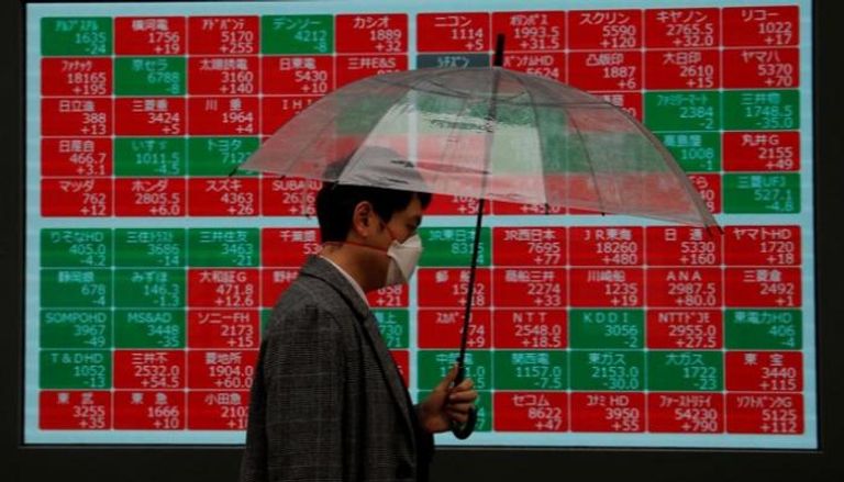 ياباني يمر أمام شاشة تظهر التداول في بورصة طوكيو 