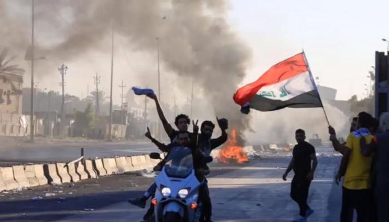 عراقي يرفع علم بلاده في مظاهرات سابقة