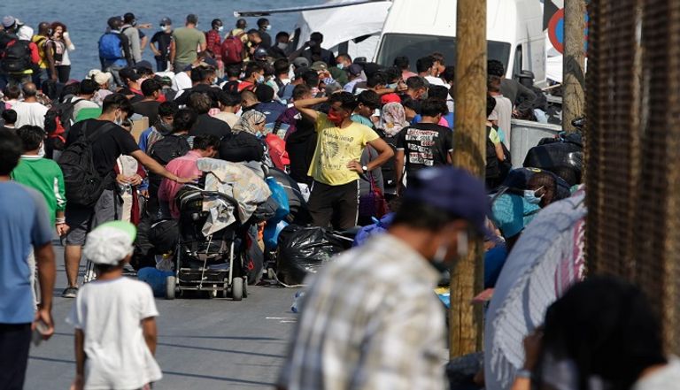 لاجئون من قرية موريا المدمرة يدخلون إلى مخيم مؤقت جديد