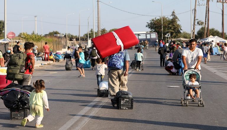 لاجئون من قرية موريا المدمرة يدخلون إلى مخيم مؤقت جديد