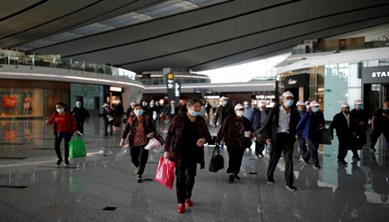 مسافرون يرتدون كمامات للوقاية من عدوى كورونا بمطار بكين الدولي