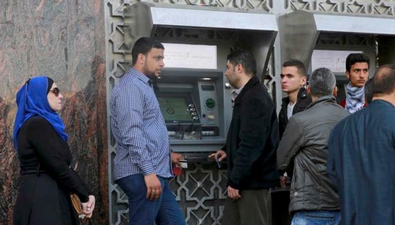 موظفون ينتظرون في طابور أمام ماكينة صرف النقود في مدينة غزة