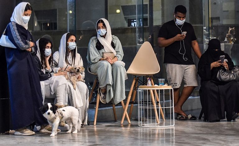 شبان وفتيات يتجمعون في المقهى للّعب مع كلاب بأحجام مختلفة