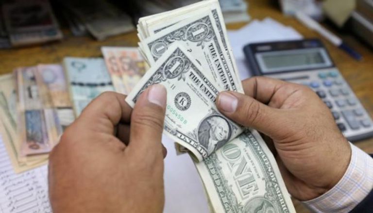 موظف بأحد مصارف ليبيا يحصي أوراقًا من فئة الواحد دولار. (أرشيفية)ليبيا