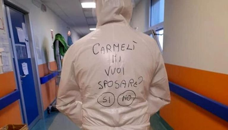 الممرض الإيطالي طالباً يد حبيبته بالكتابة على بدلة مكافحة كورونا