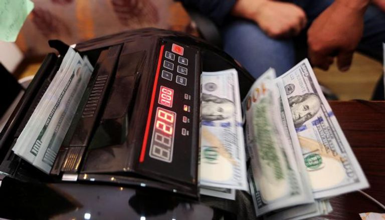 موظف بأحد مصارف ليبيا يحصي أوراقًا من فئة الـ100 دولار. (أرشيفية)ليبيا