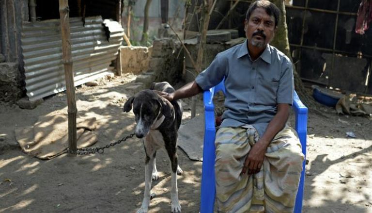 بنجلاديشي يجلس في حديقة منزله إلى جانب كلب صيد من نوع سراي