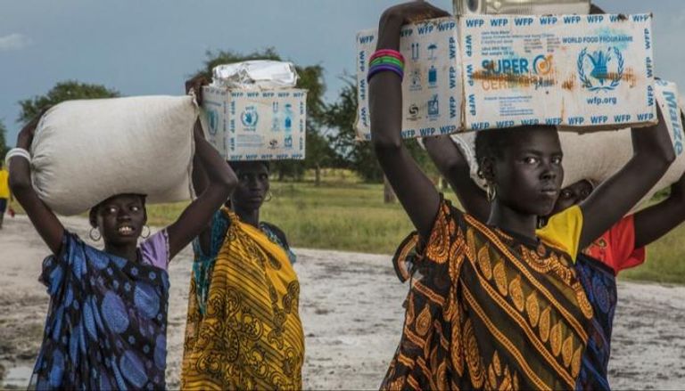مواطنون من جنوب السودان يحملون مساعدات غذائية