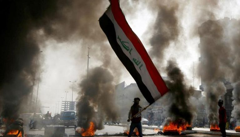 متظاهر عراقي يحمل علم بلاده خلال مواجهات سابقة