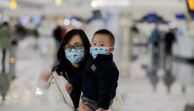 سيدة وطفلها يرتديان كمامات للوقاية من كورونا بالصين