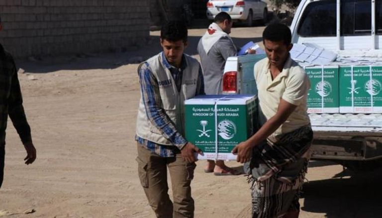 يمنيون يحملون بعض المساعدات السعودية