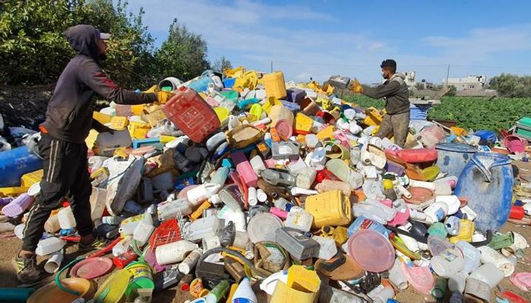 عاملان يجمعان قطع البلاستيك من النفايات تمهيدًا لإعادة تدويرها
