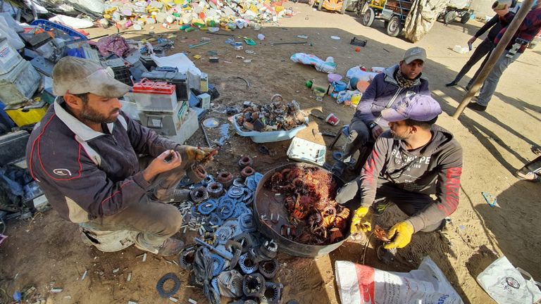 عاملان يجمعان قطع البلاستيك من النفايات تمهيدًا لإعادة تدويرها