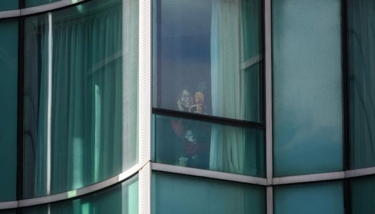 لي يونج سو خلف نافذة فندق الحجر الصحي في هونج كونج