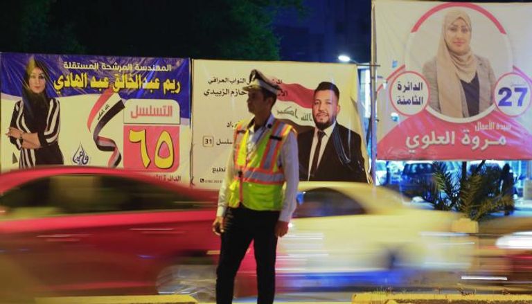 لافتات انتخابية يتقدمها شرطي مرور في العاصمة بغداد