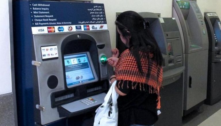 فتاة لبنانية أمام ماكينة صراف آلي