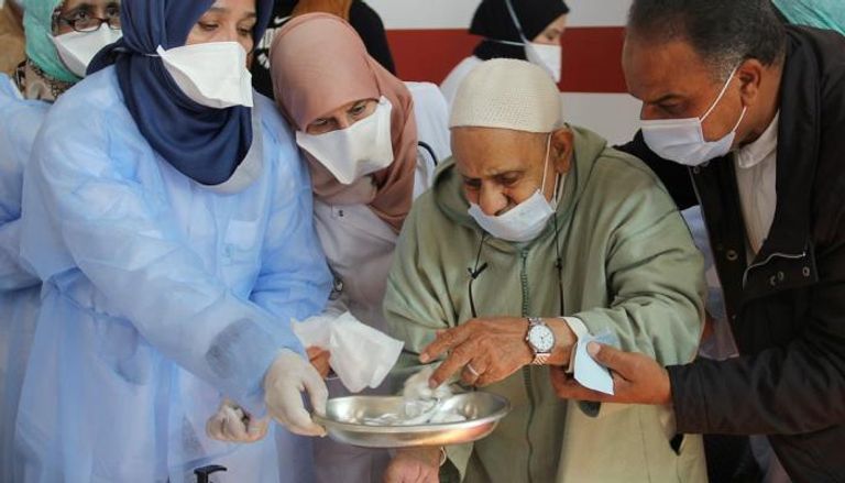 مسن مغربي يتلقى المساعدة من فريق التمريض بأحد المستشفيات